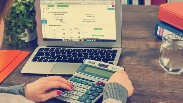 Someone working out a budget on a laptop and calculator