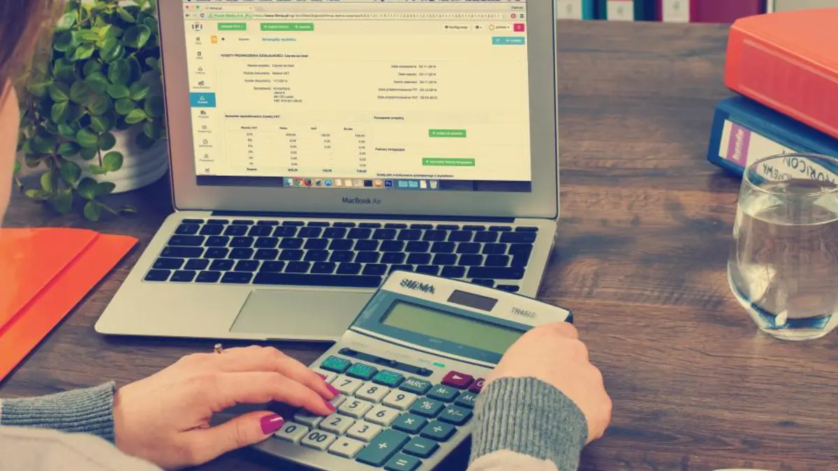 Someone working out a budget on a laptop and calculator