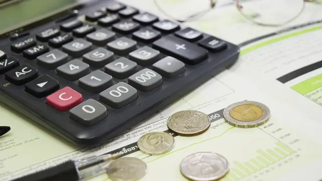 A calculator with coins and a pen