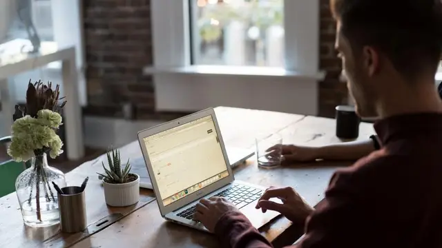 A man working at a laptop by a window